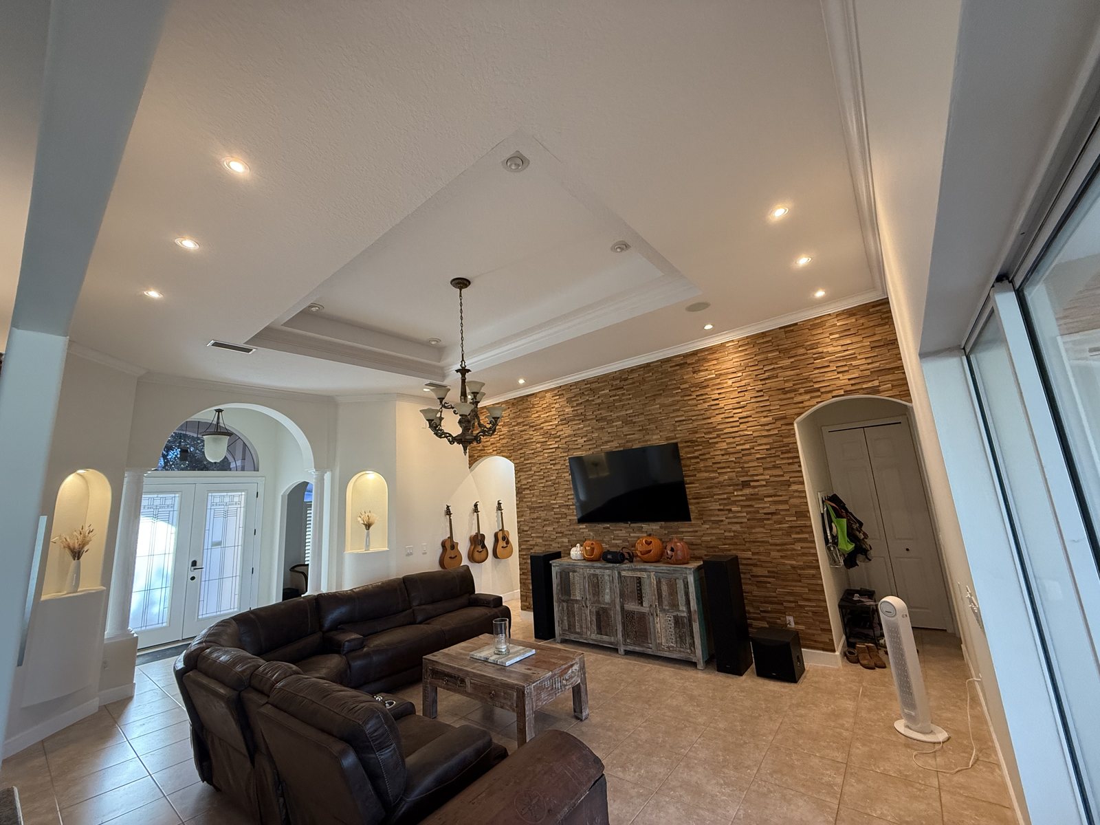 Living room with tray-ceiling recessed lighting and wall-wash cans on a wood accent wall — Grand Haven, Palm Coast